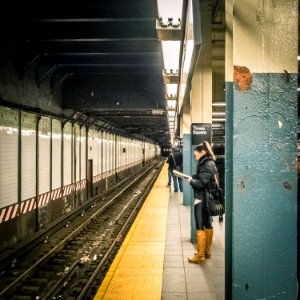 A woman reading a book while waiting for the local train
