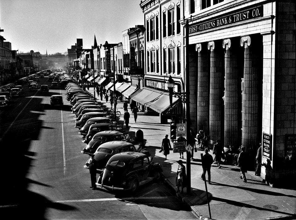 The Long Shadows: Traffic on the main street of Fayetteville, North Carolina at about five o'clock, when the workers start coming out at Fort Bragg, North Carolina. March 1941.