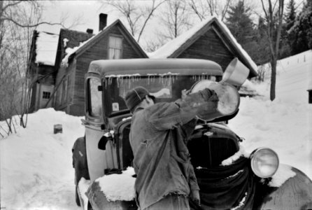 Hired man on a farm near Woodstock, Vermont, usually empties the radiator in his car every evening and refills it again with water in the morning to save the cost of antifreeze, 1940.
