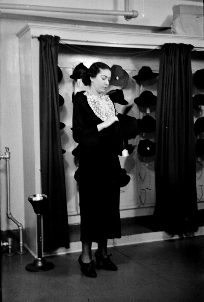 Model trying on hat for a buyer, New York City showroom of the Jersey Homesteads cooperative clothing maker, November 1936