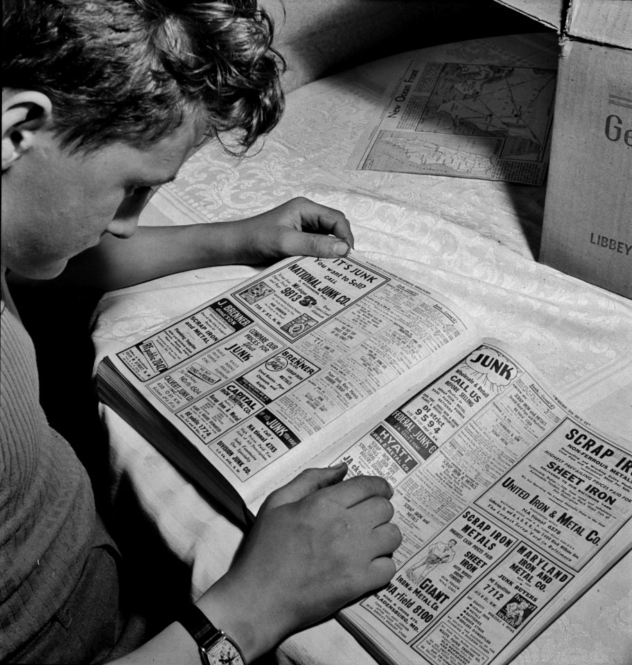 Junk: Scrap salvage campaign.This boy is looking up junk dealers in the telephone directory, wants junk dealer pick up the scrap which he collected stored in his celler Washington, D.C. May 1942.