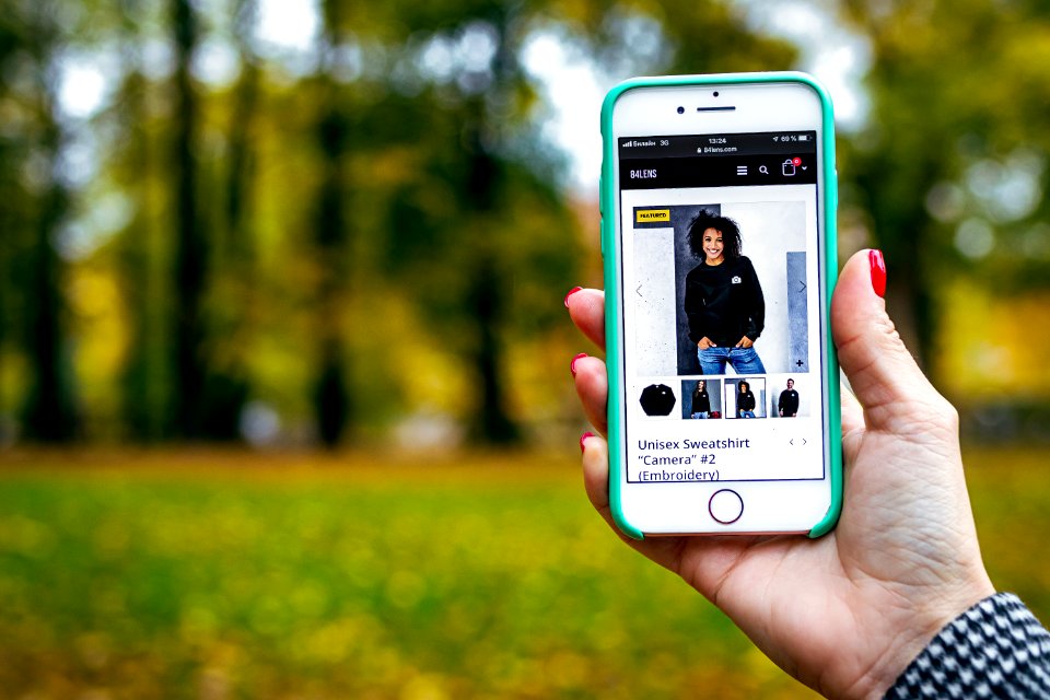 Woman hand with smartphone. Fall background.