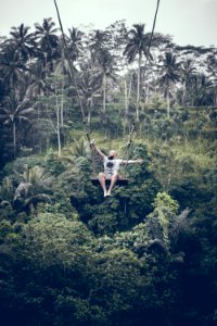 BALI, INDONESIA - DECEMBER 26, 2017: Man having fun on the swing with action camera in the jungle of Bali island, Indonesia. Rainforest, swing. photo