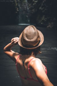 Rear view of young woman tourist with straw hat and red swimsuit in the deep jungle. Real adventure concept. Bali island. photo