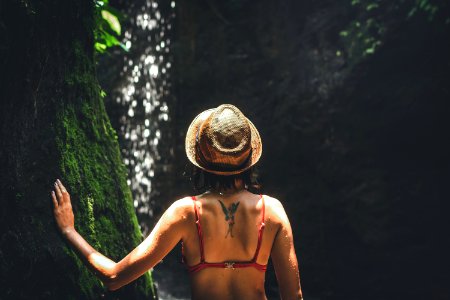 Young woman tourist with straw hat deep in the rainforest with waterfall background. Bali island. photo