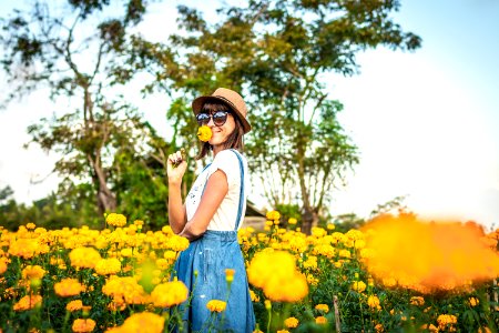 Close up portrait of happy and beautiful young woman relaxing enjoying the fresh beauty of gorgeous orange marigold flowers field in travel and holidays. Bali island. photo