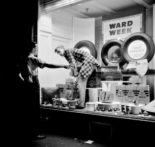 Window Dressing: Employees of a auto parts store dressing a window display in Amsterdam, New York, October 1941.