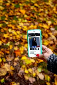 Woman hand with smartphone. Fall background.
