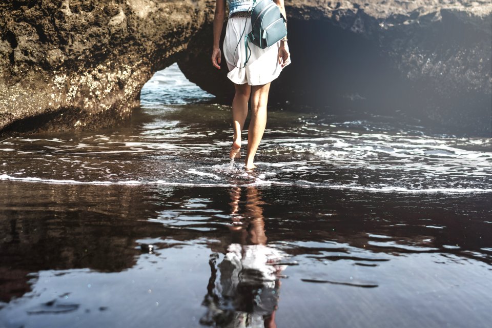 Young woman on a black sand beach, Bali island.