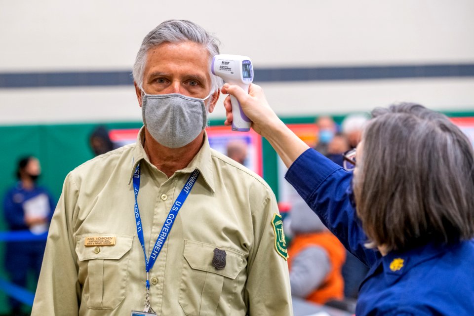 A man wearing a mask during the COVID-19 pandemic has his temperature checked.