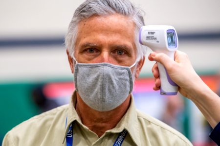 A man wearing a mask during the COVID-19 pandemic has his temperature checked. photo