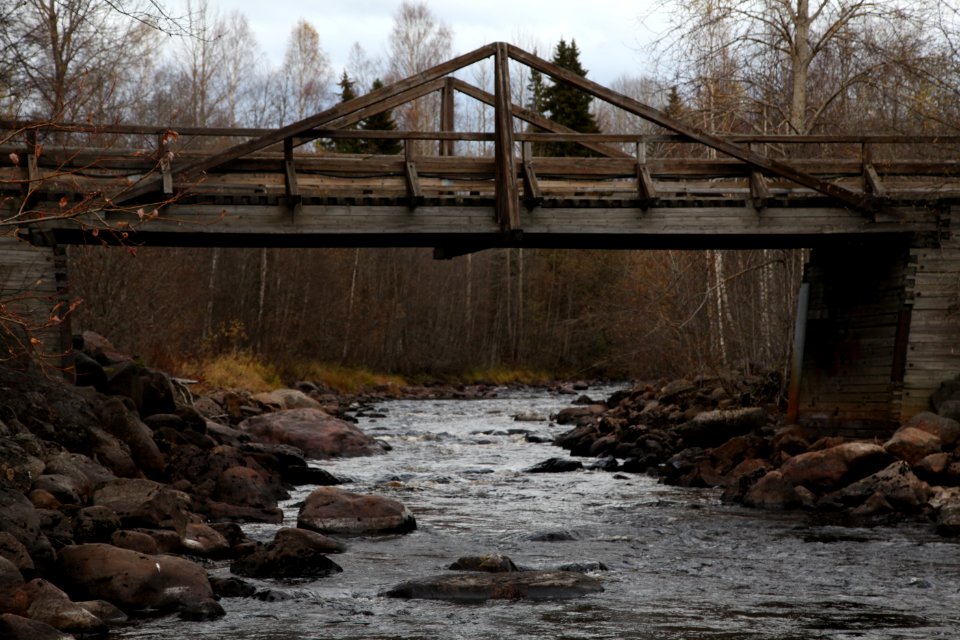 Old wood bridge across a stream on a calm gray autumn day