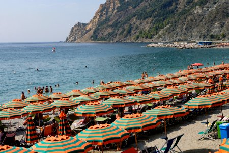 Crowded Beach With Orange and Green Sun Umbrellas at Beach Filled with Sun Umbrellas at Monterosso, Italy photo