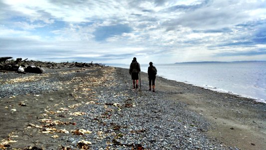 Hikers explore the shore of Puget Sound as they travel the PNT on Whidbey Island