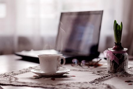 a cup of coffee, a flower and a laptop photo