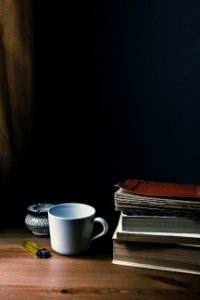 Tea mug, a lighter and a pile of books photo