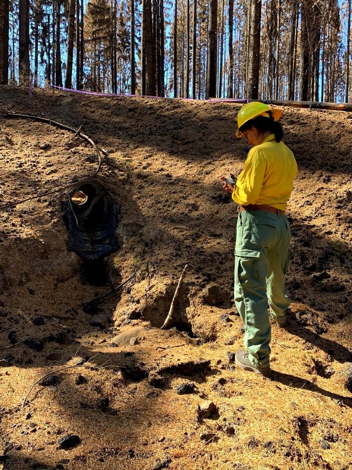 BAER Team Hydrologist Leah Tai assesses a melted plastic culvert on the Lionshead Fire