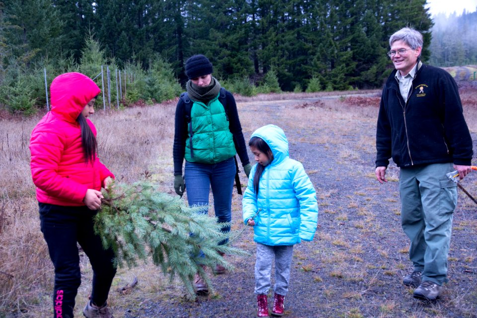 A family admires their holiday tree while a Forester smiles on, Gifford Pinchot National Forest, November 2018.  Photo by Sandy Burks.