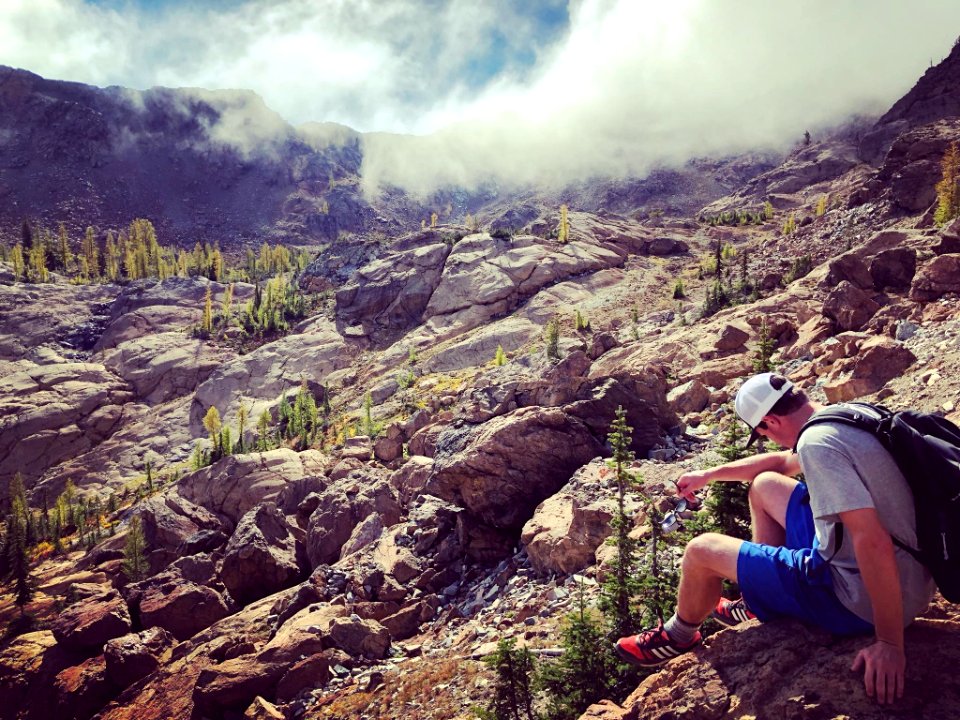 Hiker-SittingDownOnRockLarchJustStartingToTurnColor-OkaWenNFbyMasonSchuurUSFS-Sept23-2018