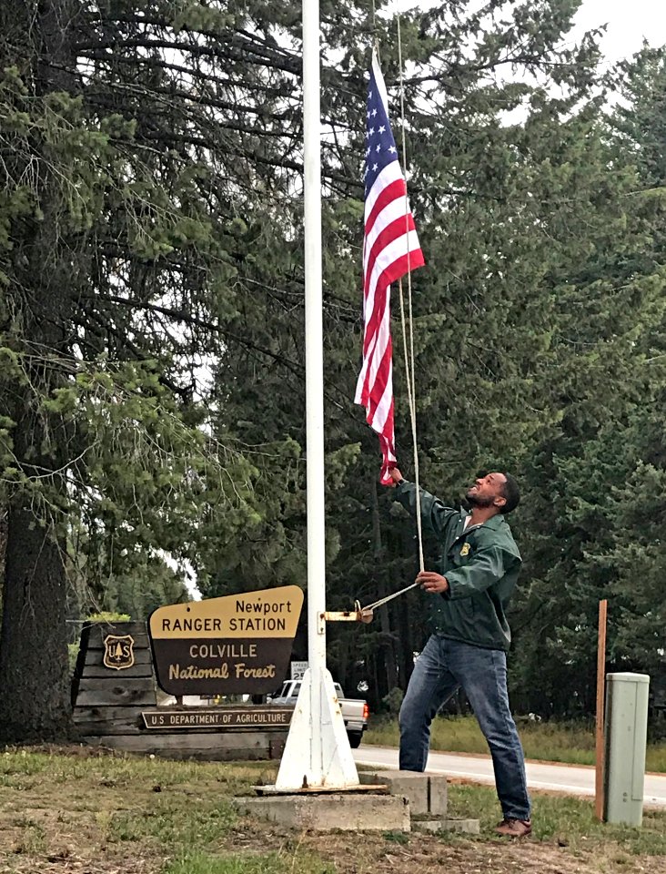 Employee raising US flag at Newport FS office