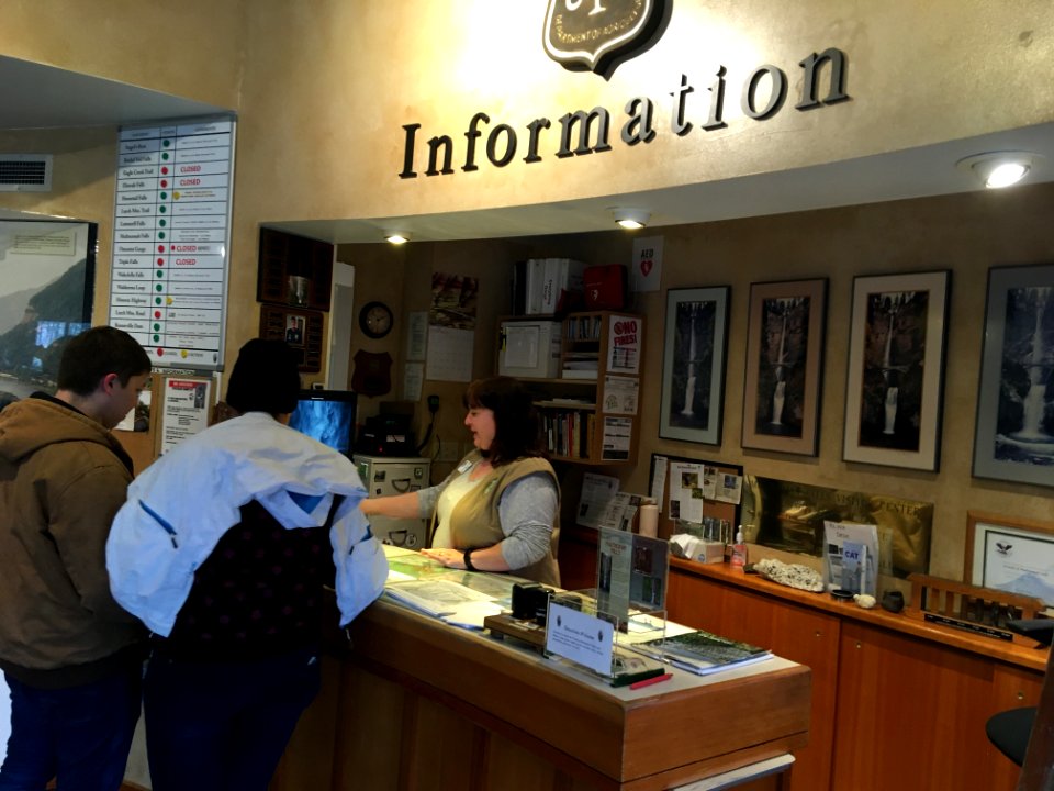 Friends of Multnomah Falls volunteer helps visitors at Visitor InformationCenter at Lodge.