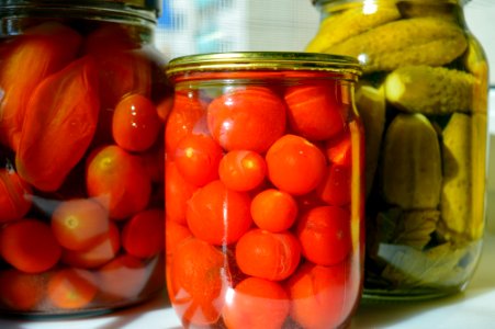 Pickled tomatoes and cucumbers in glass jars