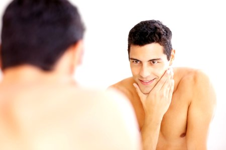 Reflection of a guy in the bathroom mirror after shaving