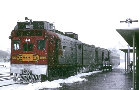 Roger Puta photographed AT&SF M-190 (gas-electric articulated motor car) with Train 26, the Pecos Valley Streamliner at the Roswell, NM station in a rare snow storm on February 3, 1964.