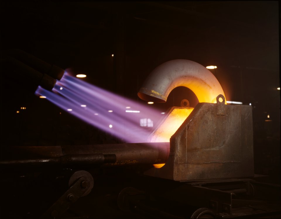Large pipe elbows for the Army are formed at Tube Turns, Inc., by heating lengths of pipe with gas flames and forcing them around a die, Louisville, Ky.