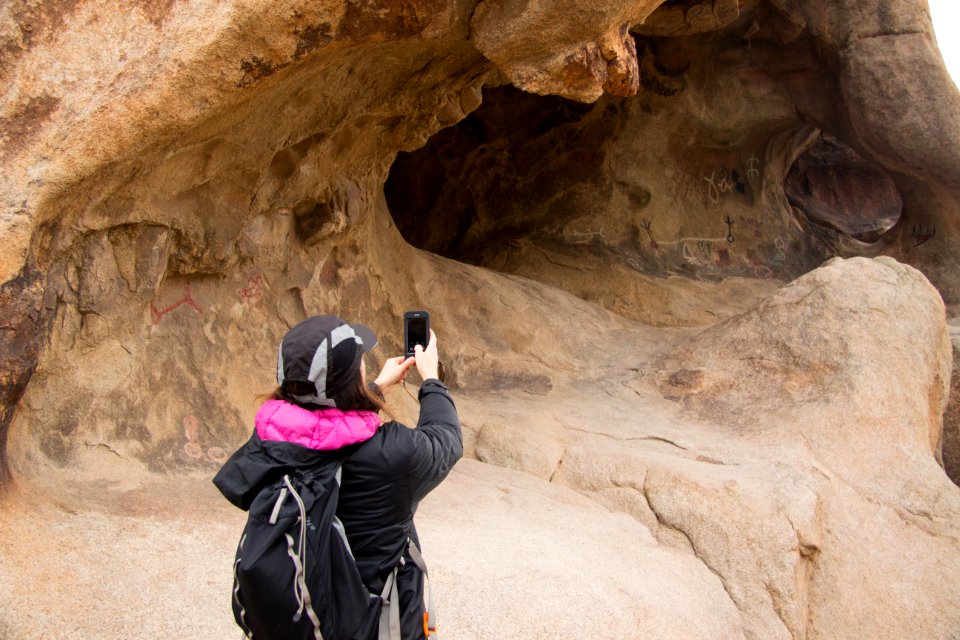Visitor photographing petroglyphs/pictographs with smartphone