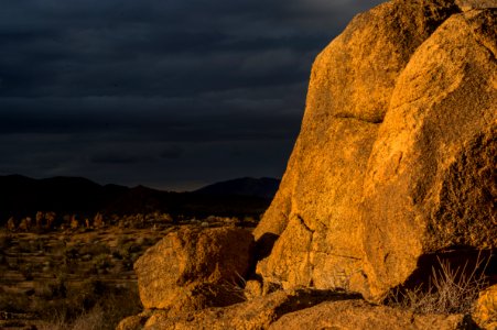 Rocks Aglow with Light Contrast with Dark Mountains photo