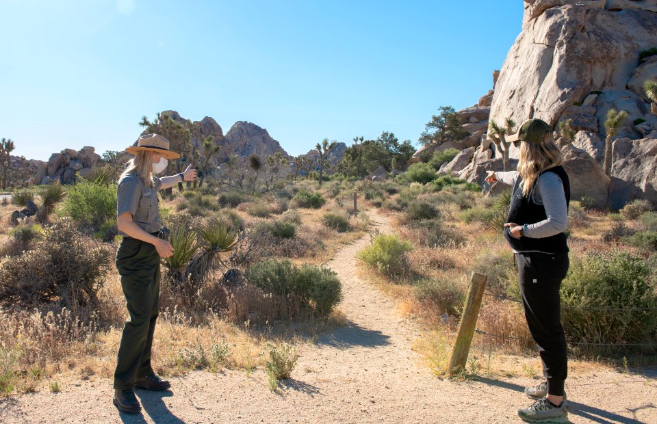 Visitor talking to a Park Ranger six feet apart in masks