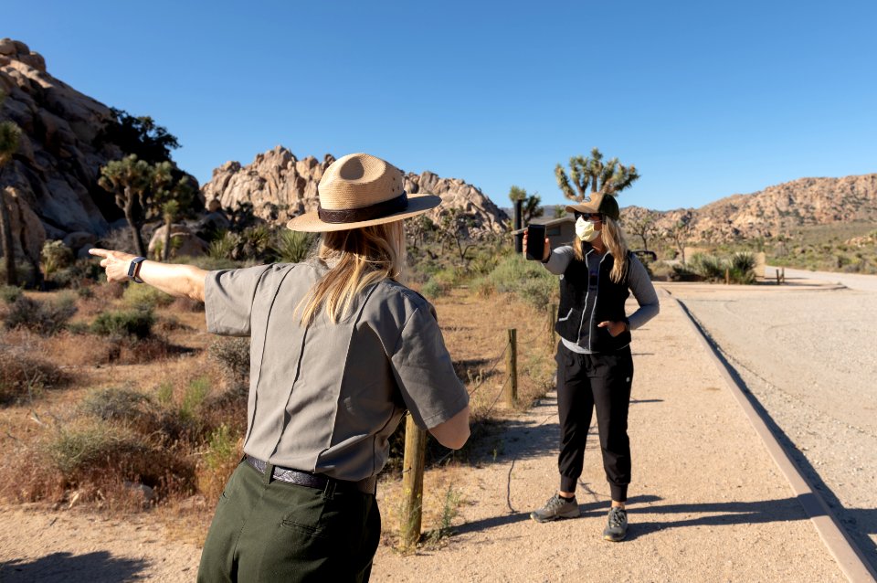 Visitor talking to a Park Ranger six feet apart in masks