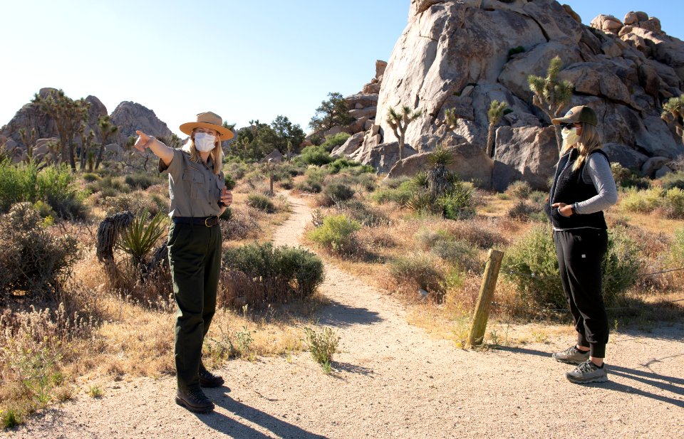 Visitor talking to a Park Ranger six feet apart in masks