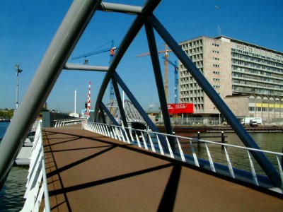 2005.04 - 'View over the metallic bowed bridge' - Amsterdam photos, a picture of the new bridge for pedestrians and cyclists, near Nemo museum in the Oosterdokr; Dutch city + geotag, Fons Heijnsbroek, The Netherlands photo