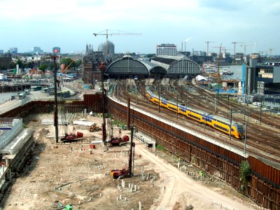 2007.08 - 'Train is leaving the City'- Amsterdam photos, a view over the last excavation of Oosterdok / Docklands area full of ramming on the concrete pilings & the old caps of Central Station; Dutch city + geotag, Arjan Heijnsbroek, The Netherlands photo