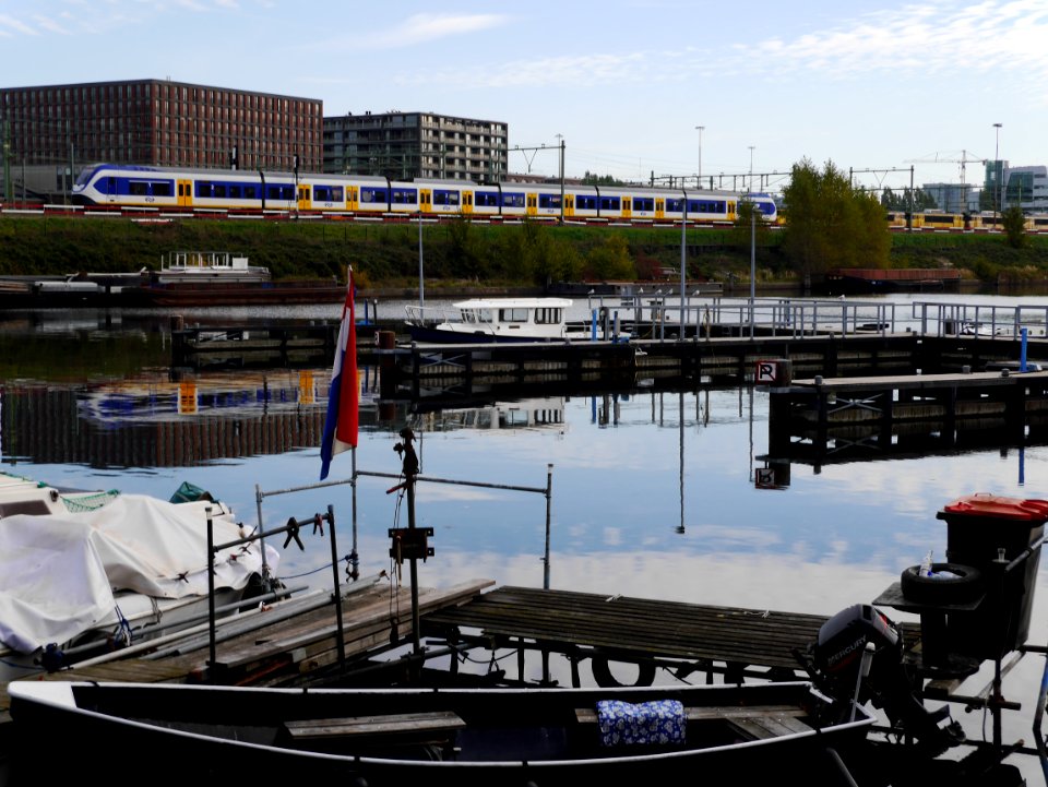 Free photo of Amsterdam city - a picture of the wide canal-water of the Dijksgracht along the train track around the city, by Fons Heijnsbroek, october 2018.