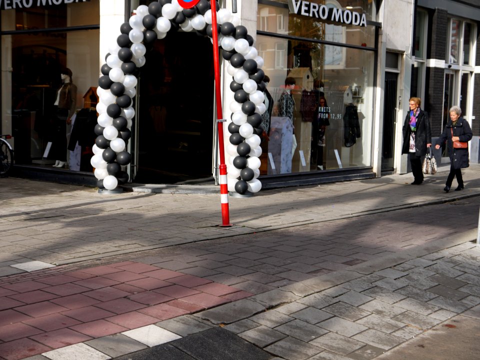 Street life with clothing shop entrance and shopping women in the Ferdinand Bolstreet in sunlight and shadows and shop-entrance; photo Amsterdam city; urban photographer Fons Heijnsbroek, 2013