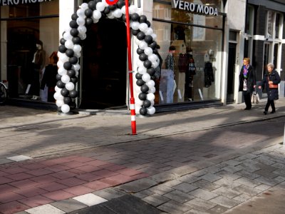 Street life with clothing shop entrance and shopping women in the Ferdinand Bolstreet in sunlight and shadows and shop-entrance; photo Amsterdam city; urban photographer Fons Heijnsbroek, 2013