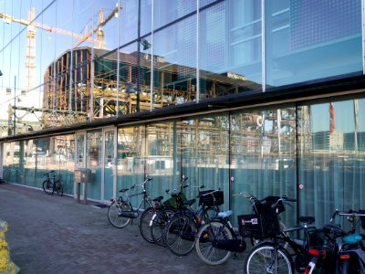 Reconstruction activities of an old metal hall-construction, reflected in the glass wall of a modern building - free photo of Amsterdam city, Fons Heijnsbroek