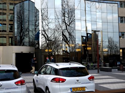 Close-up photo of reflecting windows of an office-building and people leaving the office a 4 o'clock - on the forground cars in front of the facade - near Amstel-station / Omval / Spaklerweg in Amsterdam city; - urban photography by Fons Heijnsbroek, 2013