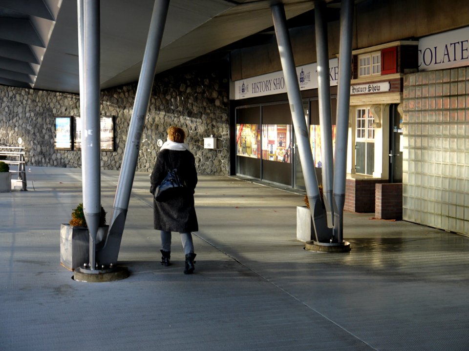 Woman walking along the waterfront IJ in the sun-light of December , in Amsterdam city; under the Piet Heinkade - a pedestrian route from city center to the Passengers Terminal on the border of river IJ; - urban photography by Fons Heijnsbroek, the Nether