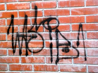 2011.05 - 'Close-up victure of a single black graffiti tag', sprayed on a brick wall, in the sun-light of Spring in the streets; geotag free urban picture, in public domain / Commons CCO;  city photography by Fons Heijnsbroek, The Netherlands