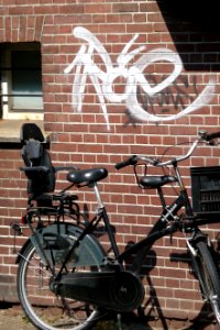 2011.04 - 'Urban still-life: parked bicycle in sun-light of Spring', in front of a brick wall with a graffiti tag; geotag free urban picture, in public domain / Commons CCO; city photography by Fons Heijnsbroek, The Netherlands photo