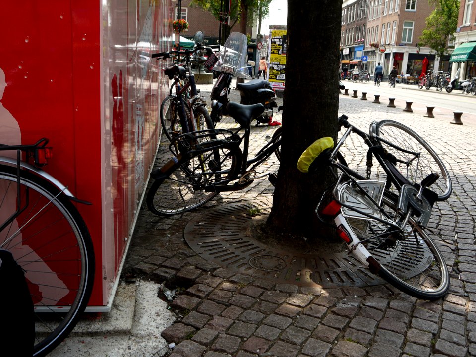 Street-view with parked bikes on the Ferdinand Bolstraat / Heineken-plein (square) to the left - with a red-colored building-barn for metro-constructions and terraces; city center of Amsterdam; - urban photography by Fons Heijnsbroek, the Netherlands, 201