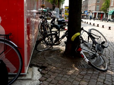 Street-view with parked bikes on the Ferdinand Bolstraat / Heineken-plein (square) to the left - with a red-colored building-barn for metro-constructions and terraces; city center of Amsterdam; - urban photography by Fons Heijnsbroek, the Netherlands, 201