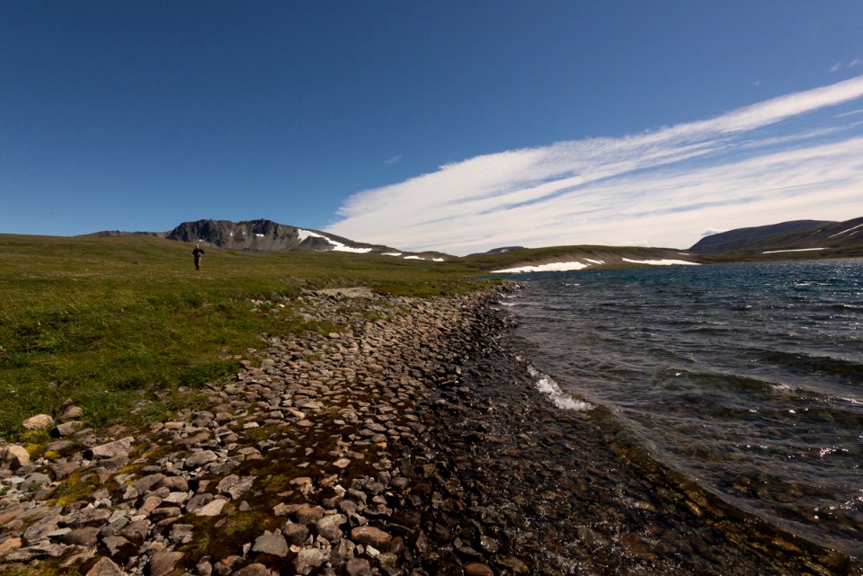 A person explore the rocky shores of Mirror Lake, Katmai Preserve NPS Photo/Russ Taylor