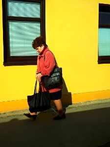 Woman Passing by a Yellow House