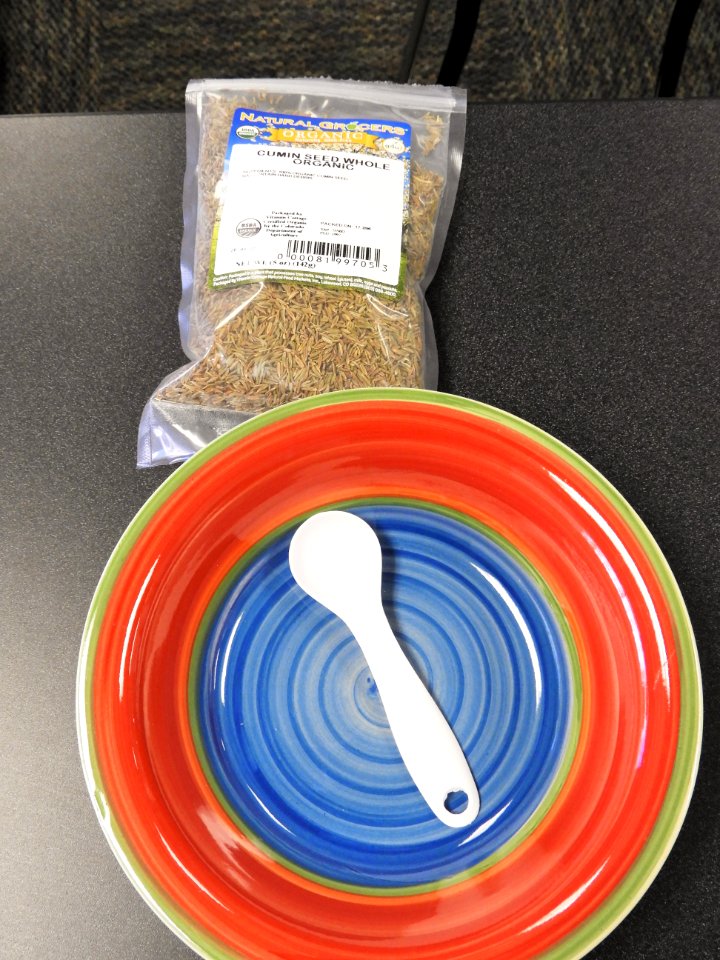 Whole cumin seeds with measuring spoon