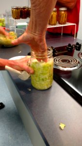 Pressing added cabbage down into mason jar
